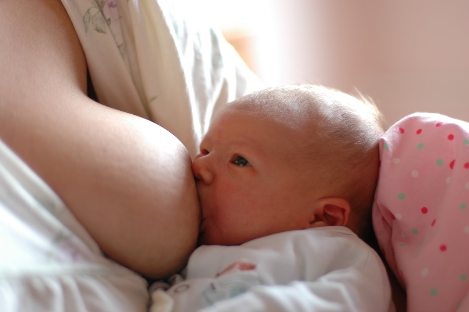 Mutter mit Schulterschmerzen beim Stillen hält ihr Baby in entspannter Haltung