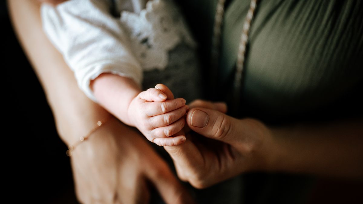 Handgelenkschmerzen nach der Geburt: Mutter hält die Hand ihres Babys